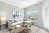 Bright and modern living room with a chic corner sofa, contemporary artwork, and abundant natural light flowing through large windows.