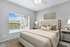 Bright and cozy bedroom with plush bed, modern decor, and large window offering scenic view.