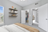 Bright and inviting bedroom with elegant wall shelves, a walk-in closet, and stylish decor, perfect for comfortable living.