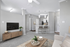 Modern living room with sleek gray walls, plush carpeting, and open-concept kitchen featuring stylish bar seating and contemporary lighting.