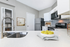 Modern kitchen with sleek white countertops, stainless steel appliances, and a decorative bowl of lemons adding a fresh touch.