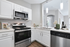 Modern kitchen with sleek stainless steel appliances, elegant white cabinetry, and stylish pendant lighting, offering a bright and welcoming ambiance.