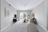 Bright, modern living room with cozy gray carpet, stylish furniture, large window, and contemporary decor.