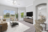 Bright and contemporary living room featuring large windows, elegant furnishings, and seamless entry to a stylish bedroom.