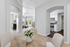 Inviting open-plan apartment interior with elegant archways, featuring a cozy dining area with a floral centerpiece, a modern kitchen with stainless steel appliances, and a bright living room with plush seating.