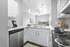 Bright and modern kitchen with elegant white cabinetry, stainless steel appliances, and an inviting open layout leading to a sunlit living room.