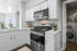 Bright and modern kitchen featuring sleek white cabinetry, stainless steel appliances, and a convenient in-unit laundry area.