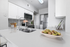 Sleek modern kitchen with gleaming white countertops, stainless steel appliances, and elegant tile backsplash.