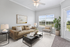 Bright and inviting living room with plush beige sofa, modern armchair, and abundant natural light through large windows.