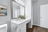 Elegant bathroom showcasing a sleek vanity with a large mirror, modern lighting, and stylish decor in a refined setting.