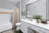 Modern bathroom with stylish decor, featuring a large mirror, bright white counter, and elegant shower curtain.
