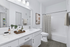 Modern bathroom design with sleek white vanity, stylish fixtures, and a chic tiled bathtub.
