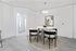 Modern dining area with sleek round table, stylish black chairs, artistic wall decor, and elegant lighting, creating a welcoming atmosphere.