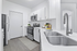 Modern kitchen with sleek stainless steel appliances, elegant white cabinetry, and a stylish dual sink set against crisp white countertops.