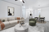 Modern open-concept living room with chic decor, featuring a cozy beige sofa, stylish artwork, and a spacious dining area for elegant entertaining.