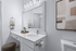 Modern bathroom with sleek white vanity, large mirror, elegant lighting, and minimalist decor.