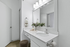 Modern bathroom with a sleek white vanity, large mirror, and stylish lighting, enhanced by floral accents for a refreshing ambiance.