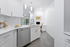 Modern kitchen with sleek white cabinetry, stainless steel appliances, and elegant tile backsplash, leading to a cozy workstation nook with natural light.