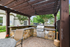 Charming outdoor grill area with a stone grill counter under a wooden pergola, ideal for entertaining.