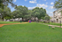 Spacious apartment community with lush green dog park, and modern residences set against a bright, blue sky.