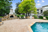 Inviting outdoor space with a crystal-clear swimming pool, cozy stone fireplace, and lush greenery, perfect for relaxation and gatherings.