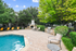 Inviting outdoor space featuring a swimming pool, cozy fireplace, and stylish seating surrounded by lush greenery.