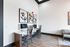 Modern business center with sleek desks, dual computers, artistic wall d&eacute;cor, and stylish seating on elegant wood flooring.