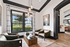 Bright and inviting clubhouse with large windows offering serene garden views, featuring elegant leather chairs and a modern coffee table.