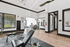 Bright and modern fitness center featuring high-end gym equipment, expansive windows, and stylish wood flooring.