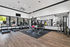 Modern fitness center with treadmills, weight racks, and exercise equipment on elegant wooden flooring.