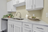 Modern kitchen with elegant white cabinets, sleek countertops, double sink, and a stylish stainless steel dishwasher.