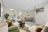 Inviting living area with stylish decor, featuring a plush green sofa, modern coffee table, and open dining space, perfect for entertaining in a cozy apartment setting.