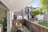Charming apartment balcony with a cozy seating area and lush greenery, offering serene views of a beautifully landscaped courtyard.