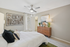 Elegant bedroom with modern decor, featuring a stylish wooden dresser, contemporary art, and a ceiling fan, offering a serene and inviting atmosphere.