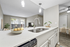 Contemporary open-concept kitchen and living area featuring sleek white countertops, modern pendant lighting, and a view of the cozy dining space.