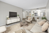 Chic open-plan living room with modern decor, cozy seating, and sleek kitchen bar featuring stylish stools.