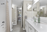 Modern bathroom with sleek white vanity, elegant decor, and a view into a bright dining area.