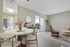 Modern apartment interior showcasing a stylish dining area with a marble table, open-concept living space with chic seating, and abundant natural light from sliding glass doors.
