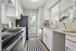 Bright, modern galley kitchen with sleek white cabinetry, stainless steel appliances, and ample natural light.