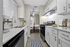 Sleek modern kitchen with white cabinets, stainless steel appliances, and a cozy dining area in the background.