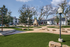 Charming outdoor space with a cozy stone path, lush green lawns, and stylish lighting, surrounded by trees and modern architecture.