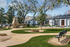 Charming outdoor space with a cozy stone fireplace, lush green lawns, winding pathways, and a serene seating area, perfect for relaxation and enjoyment.