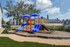 Vibrant playground with colorful slides and climbing equipment set in a sunny, family-friendly community.