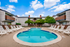 Inviting apartment community pool area with lounge chairs under a clear blue sky.