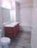 Bright and welcoming bathroom featuring modern fixtures, elegant wood cabinetry, and a sleek combination of tile and laminate flooring.