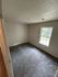 Inviting bedroom with plush carpeting, ample natural light from a large window, and freshly painted walls.