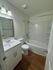 Elegant bathroom featuring modern fixtures, sleek white vanity, and a cozy bathtub with stylish wood flooring.
