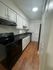 Modern kitchen with sleek black appliances, white cabinetry, and elegant wood floors.