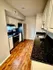 Modern kitchen with sleek black countertops, stainless steel appliances, and warm wood flooring.