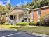 Charming apartment building with stylish brick exterior, nestled in a lush green landscape under a clear blue sky.